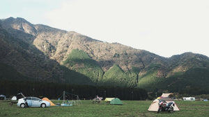 Campground with cars and colorful dome tents set among green hills