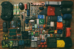 Assorted hiking and mountaineering gear laid out on a black tarp before a trip