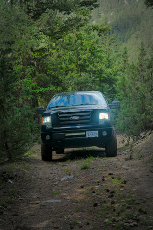 A truck driving on a remote dirt forest trail through the mountains