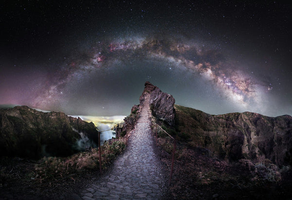 The Milky Way arching over a rocky mountain path under a dark night sky