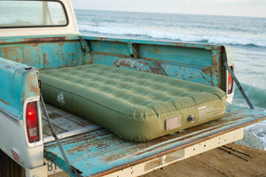 Basecamp Mattress inflated in a vintage truck bed on the beach at sunset