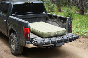 Basecamp Mattress self-inflating camping mattress inflated in a pickup truck bed at a forest campsite